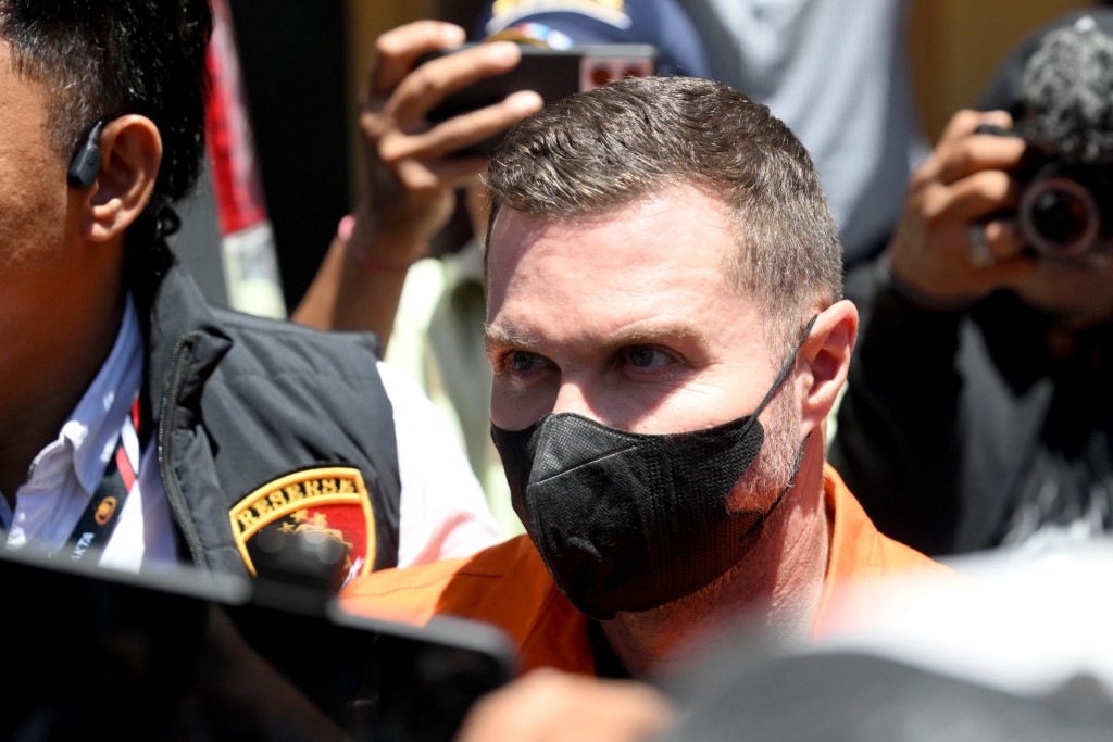 Photo by SONNY TUMBELAKA / AFP  Scottish national Steven Lyons (C) is escorted by police officers at the Bali police headquarters in Denpasar, on Indonesia resort island of Bali on March 31, 2026.