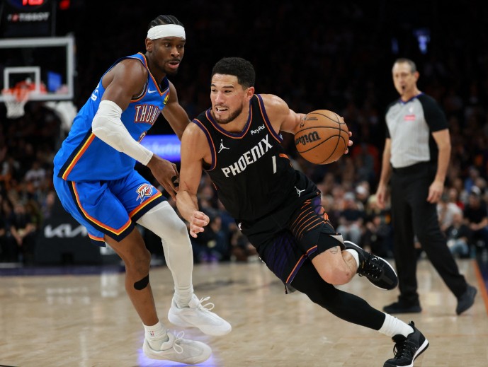 Devin Booker drives to the basket against Oklahoma City Thunder guard Shai Gilgeous-Alexander.  REUTERS