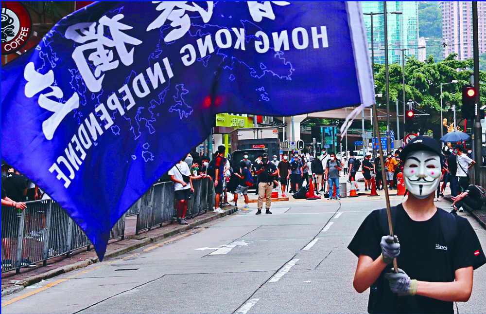 A man waves a flag at Sunday's protests. Inset: Tam Yiu-chung, who says speaking against the government should not fall under the proposed law, but actions to overthrow it would. REUTERS, SING TAO A man waves a flag at Sunday's protests. Inset: Tam Yiu-chung, who says speaking against the government should not fall under the proposed law, but actions to overthrow it would. REUTERS, SING TAO