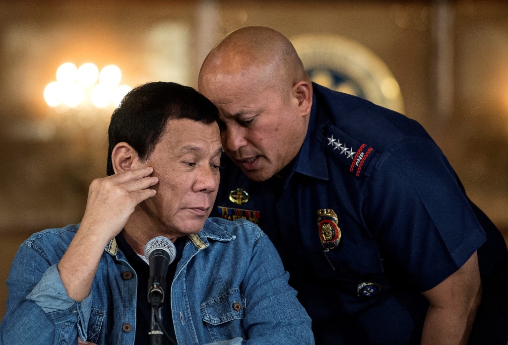Photo by NOEL CELIS / POOL / AFP  This file photo taken on January 30, 2017 shows Philippine President Rodrigo Duterte (L) listening to Ronald Dela Rosa (R), then-director general of the Philippine National Police (PNP), during a press conference at the Malacanang palace in Manila.