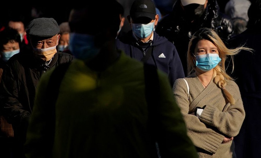 People wearing protective masks walk on a street, following the new cases of the coronavirus disease. (Reuters) People wearing protective masks walk on a street, following the new cases of the coronavirus disease. (Reuters)