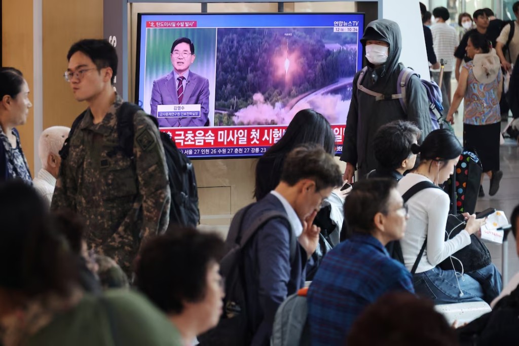 People sit in front of a TV broadcasting a news report on North Korea firing multiple ballistic missiles toward the sea off its east coast, at a railway station in Seoul, South Korea, October 12, 2026. REUTERS/Kim Hong-Ji