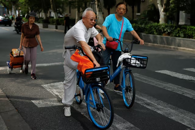 Elderly people ride bikes from a bike-sharing service on a street in Shanghai, China September 28, 2024. REUTERS/Tingshu Wang