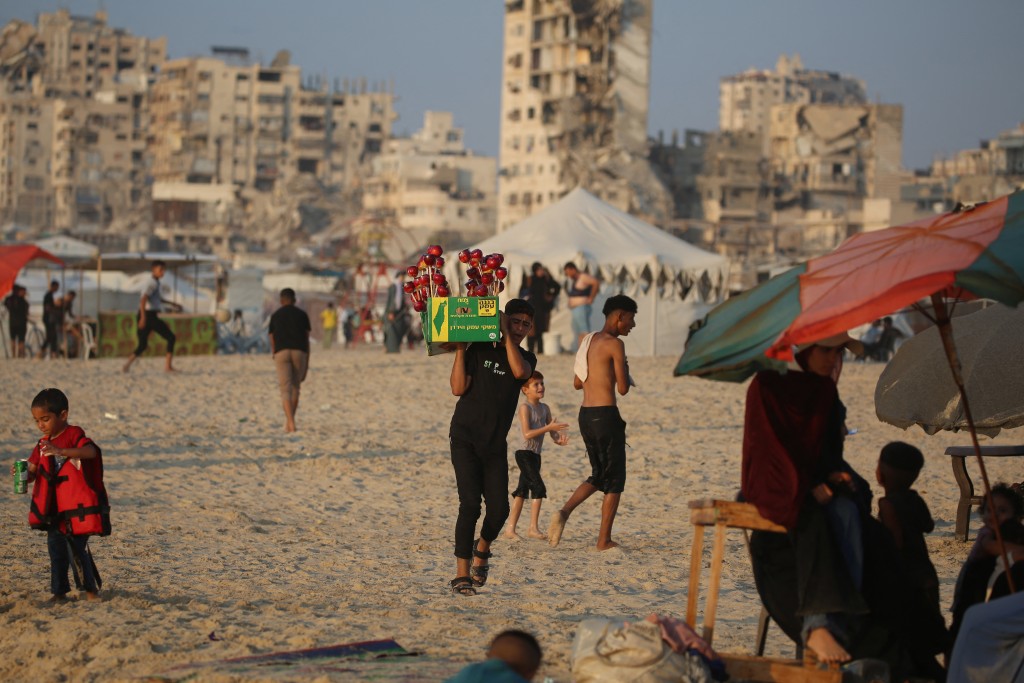 Displaced Palestinians gather along on the beach front in Gaza City on August 14, 2026. (Photo by Eyad Baba / AFP)