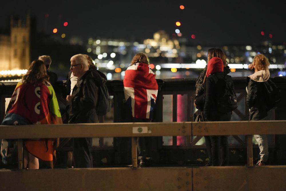 A woman draped with a Union flag waits with other people in the queue near Westminster Palace to pay their respect to the late Queen Elizabeth II during the Lying-in State, at Westminster Hall in London, Thursday, Sept. 15, 2022. (AP) A woman draped with a Union flag waits with other people in the queue near Westminster Palace to pay their respect to the late Queen Elizabeth II during the Lying-in State, at Westminster Hall in London, Thursday, Sept. 15, 2022. (AP)