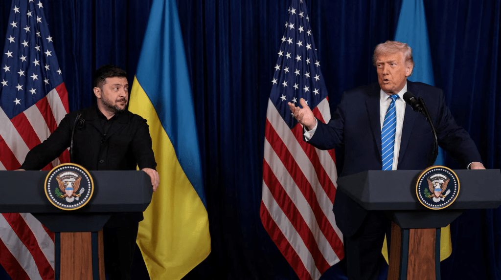 Ukrainian President Volodymyr Zelenskiy listens to U.S. President Donald Trump, after Trump said that Russian President Vladimir Putin expressed willingness to help Ukraine "succeed", during a press conference at Trump's Mar-a-Lago club, in Palm Beach, Florida, U.S., December 28, 2025. REUTERS/Jonathan Ernst
