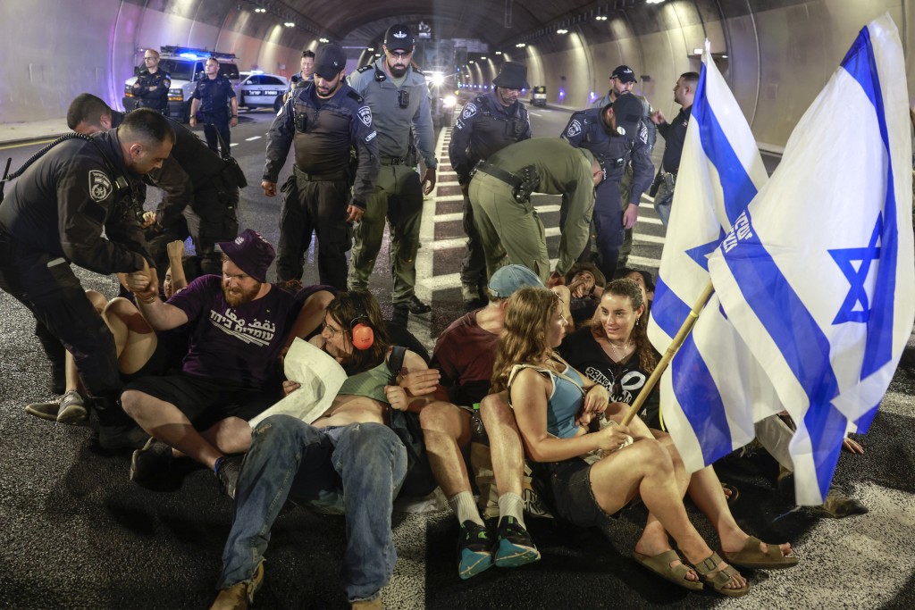  Israeli police remove demonstrators blocking traffic in a tunnel, as families and supporters of Israelis held hostage by Hamas militants in Gaza since the October 7, 2023 attacks, stage a protest calling for government action to secure their release in Jerusalem on August 17, 2025. Demonstrators took to the streets across Israel on August 17 calling for an end to the war in Gaza and a deal to release hostages still held by militants, as the military prepares a new offensive. (Photo by Menahem Kahana / AFP)