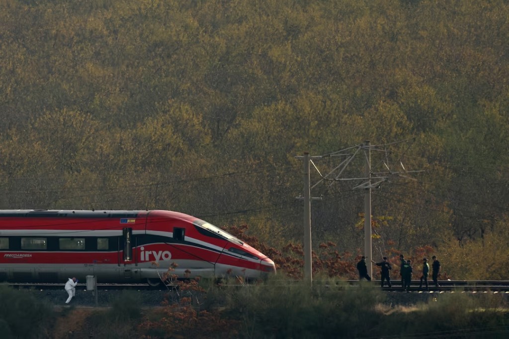  Members of the Spanish Civil Guard and police stand on the railroad tracks as an investigator works at the site of the collision where two high-speed trains crashed between the towns of Mora and Orgaz, near Toledo, Spain, October 30, 2026. REUTERS/Susana Vera 