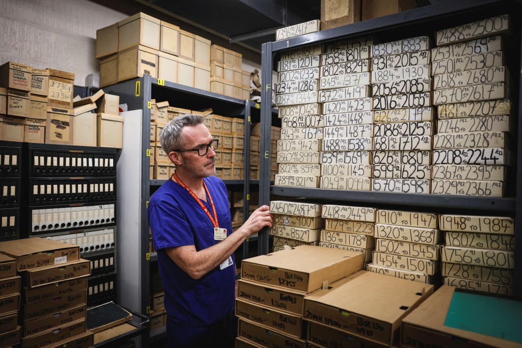 Photo by ADRIAN DENNIS / AFP  This photo taken on January 14, 2026 shows consultant gastroenterologist Kevin Monahan looking through samples in a storeroom at St Mark’s hospital at Northwick Park in Harrow, west London.