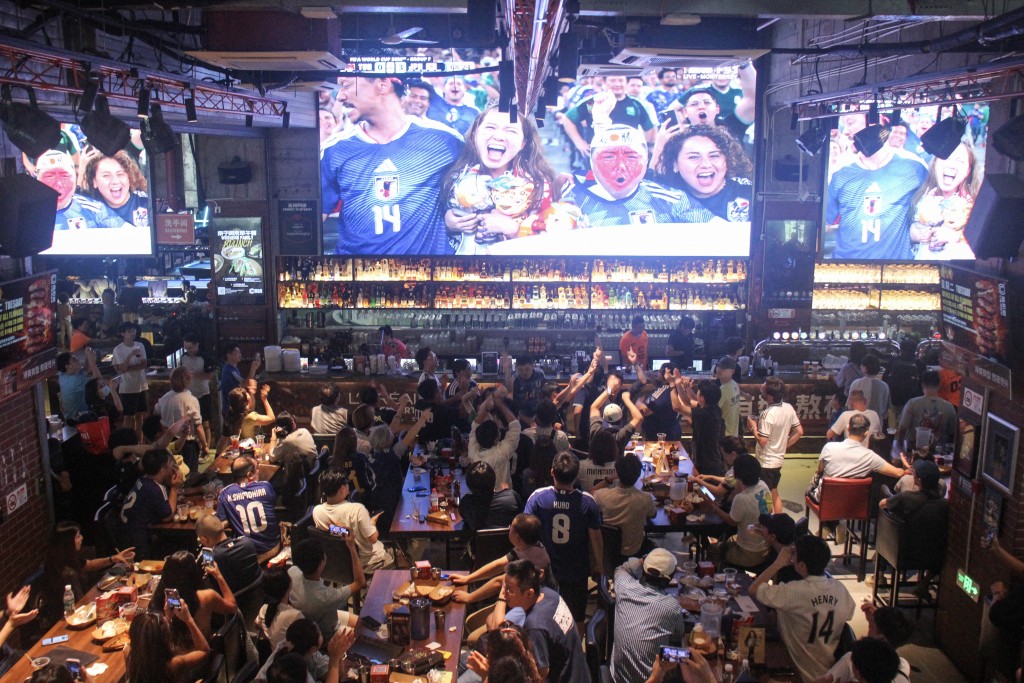 Photo by REBECCA BAILEY / AFP  This photo taken on June 21, 2026 shows Chinese fans of the Japan football team watching the 2026 World Cup Group F football match between Japan and Tunisia at a bar in Shanghai, as the game takes place at the Monterrey Stadium in Guadalupe, Mexico.