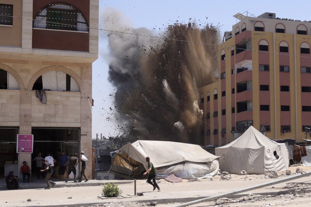 Palestinians rush for cover as smoke billows after an Israeli strike on a building in Jabalia in the northern Gaza Strip on August 20, 2025. Israel's defence minister approved a plan on August 20, for the conquest of Gaza City and authorised the call-up of around 60,000 reservists, piling pressure on Hamas as mediators push for a ceasefire. (Photo by BASHAR TALEB / AFP)