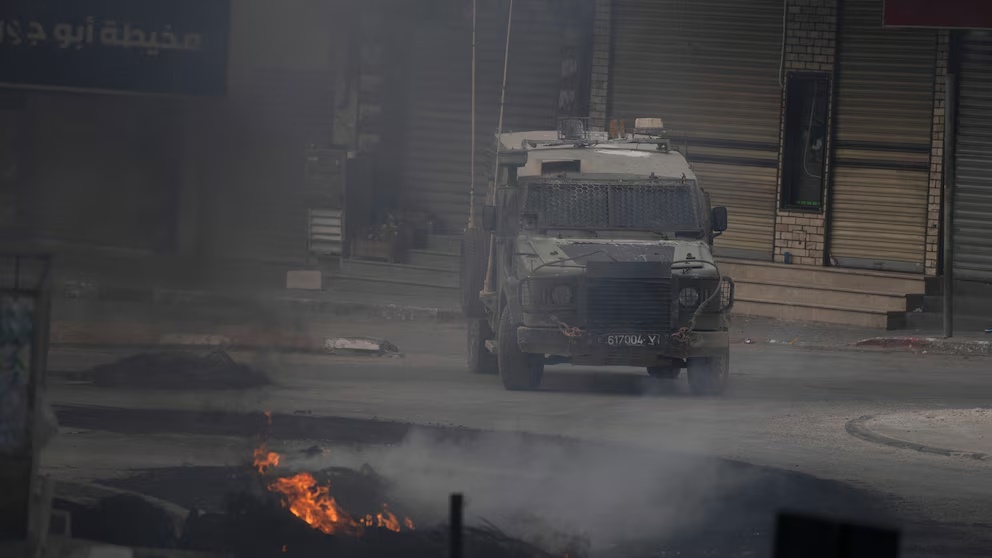 An Israeli armoured vehicle moves near burning tires during clashes with Palestinian demonstrators in the West Bank city of Jenin, Wednesday, May 22, 2024. (AP Photo/Leo Correa) An Israeli armoured vehicle moves near burning tires during clashes with Palestinian demonstrators in the West Bank city of Jenin, Wednesday, May 22, 2024. (AP Photo/Leo Correa)