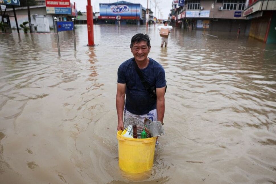 Men wade through floodwater carrying their belongings after heavy rain in the northern states of Malaysia, bordering Thailand, in Kangar, Malaysia. REUTERS/Hasnoor Hussain