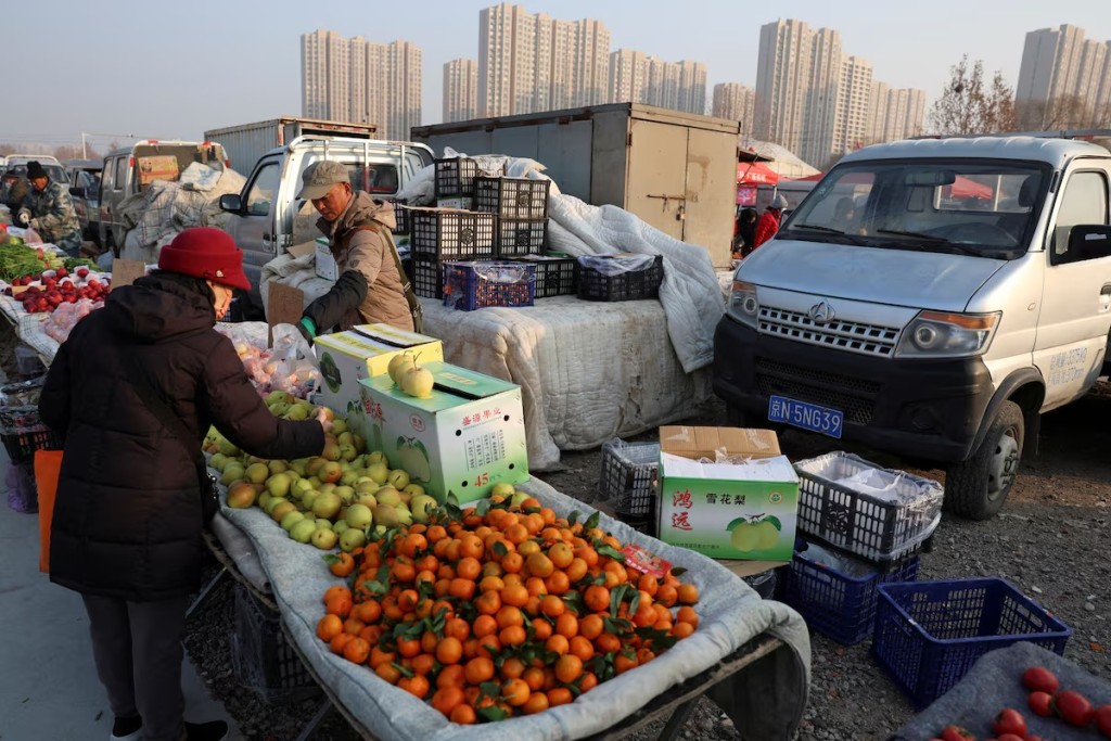 A fruit vendor attends to a customer at an outdoor market in Beijing, China January 12, 2024. REUTERS
