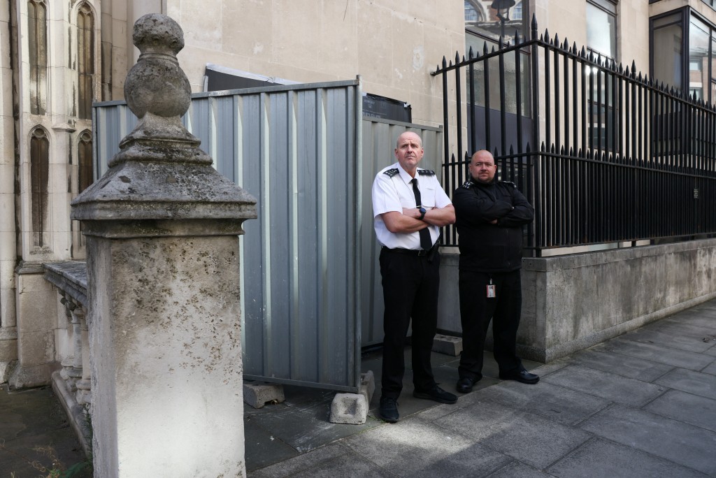 Security guards stand in front a screen covering a new mural by anonymous artist Banksy on the Royal Courts of Justice in London, Britain. (Reuters)