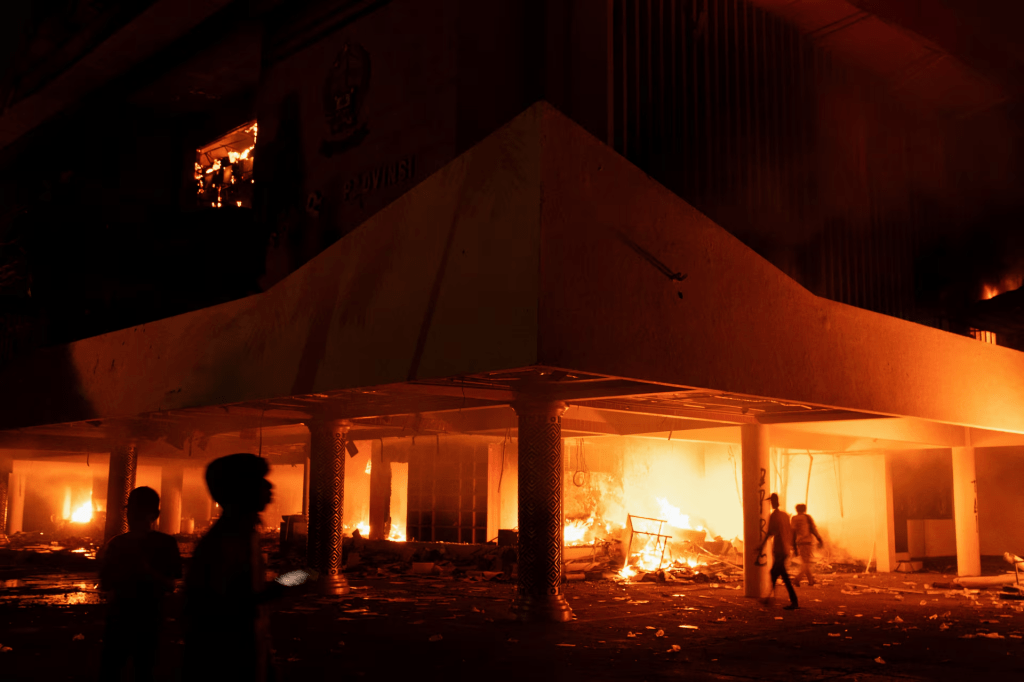 Protesters gather near the burning regional parliament building, during a protest after a motorcycle taxi driver died after being struck and run over by a police tactical vehicle during Thursday's protest against parliamentarians' allowances, in Makassar, South Sulawesi province, Indonesia, August 30, 2025. REUTERS/Iqbal Lubis