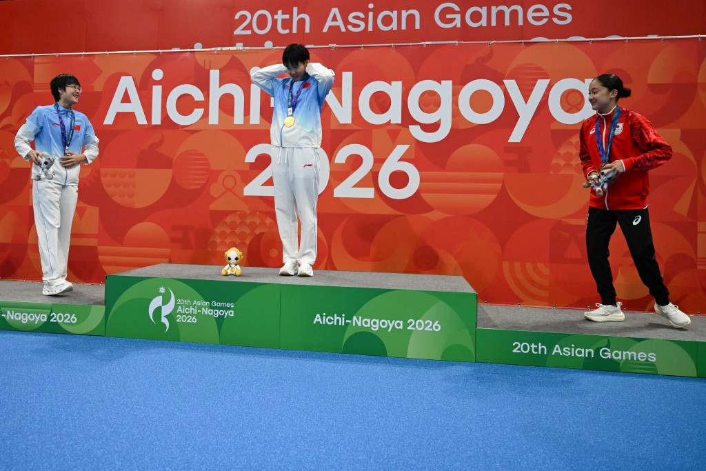 Gold medallist China's Yu Zidi (C), silver medallist China's Ke Wenxi (L) and bronze medallist Japan's Mio Narita (R) celebrate on the podium during the victory ceremony of the women's 400m individual medley swimming event during the 2026 Asian Games at the Tokyo Aquatics Centre in Tokyo on September 23, 2026. (Photo by ANDREW CABALLERO-REYNOLDS / AFP)