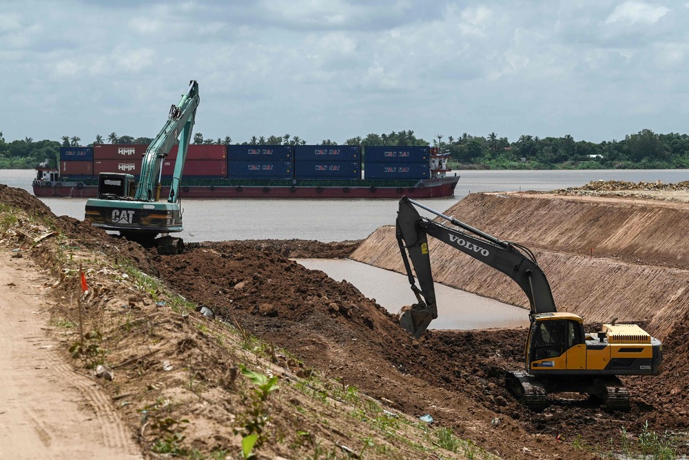 This photo taken on July 9, 2024, shows a ship transporting containers along the Mekong River (back) as excavators are used to dig the Funan Techo canal along the Prek Takeo channel in Kandal province. (AFP) This photo taken on July 9, 2024, shows a ship transporting containers along the Mekong River (back) as excavators are used to dig the Funan Techo canal along the Prek Takeo channel in Kandal province. (AFP)
