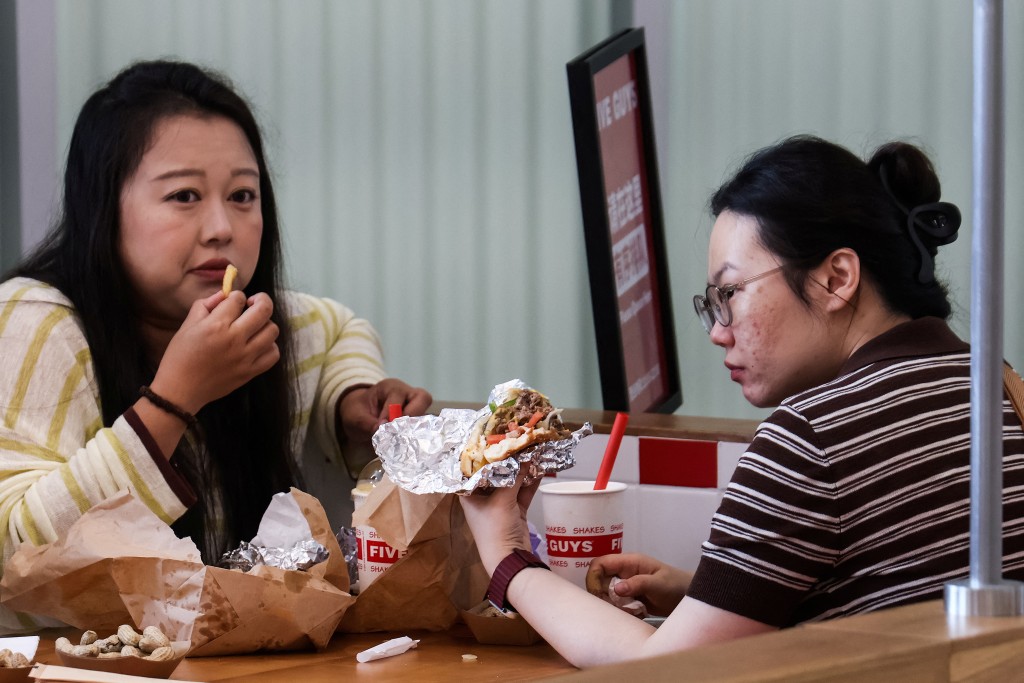 Two women eat at a Five Guys fast-food restaurant after the U.S. burger chain opened its first two locations earlier this month, in Beijing, China, August 15. (Reuters)