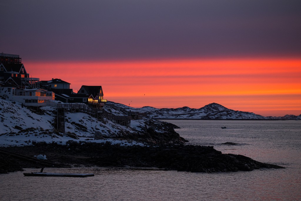 Light glows from homes along the shore as the sun sets over the coastline in Nuuk, Greenland, on January 23, 2026.An Air Greenland aircraft rolls along the runway after landing at Nuuk Airport, Greenland, on January 23, 2026. (Photo by Jonathan NACKSTRAND / AFP)