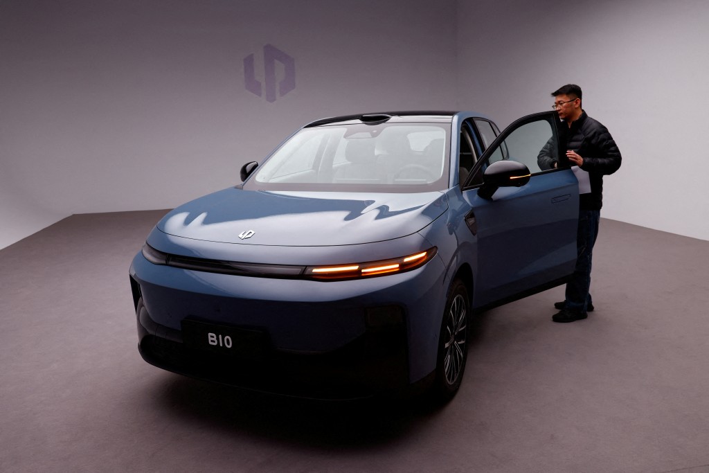 A staff member opens the door of a Leapmotor B10 EV car during a media event, in Beijing, China February 28, 2025. REUTERS/Tingshu Wang
