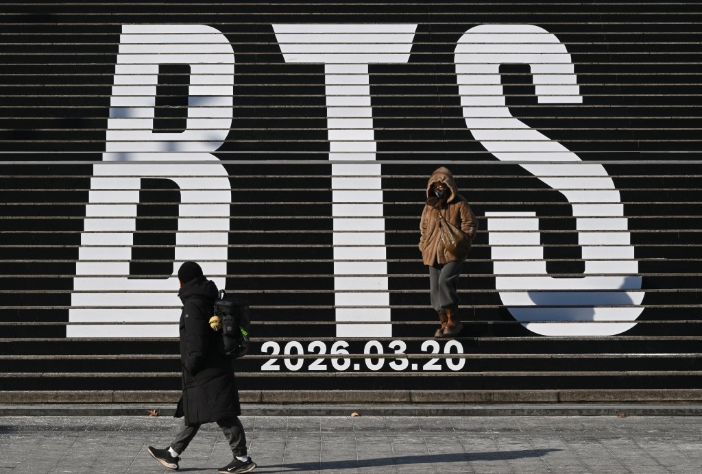 Photo by JUNG YEON-JE / AFP  Pedestrians walk along the stairs displayed with the BTS logo and release date of BTS' 2026 album at Gwanghwamun Square in Seoul on January 14, 2026.