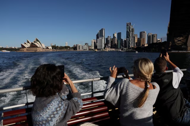 People take photos of the Sydney Opera House and Central Business District (CBD) skyline in Sydney, Australia, July 9, 2025. REUTERS/Hollie Adams/ File Pjhoto