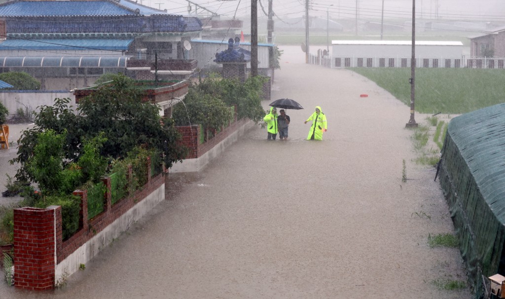 Policemen evacuate a resident from a flooded area following torrential rains in Changnyeong, South Korea, July 17, 2025. (Reuters)