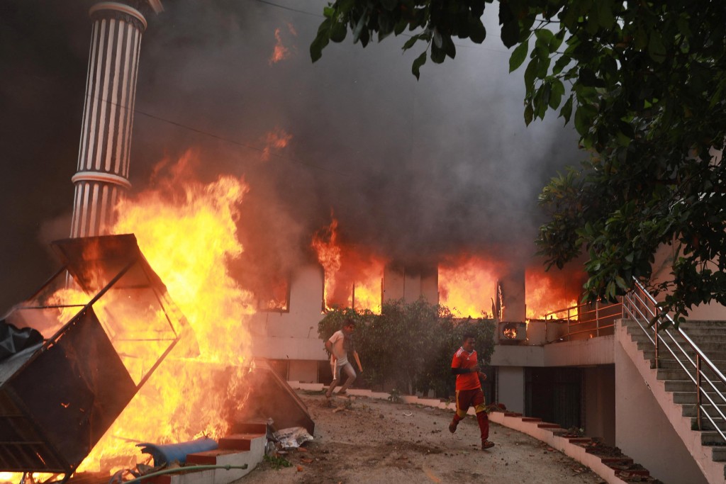 Demonstrators run past flames outside the burning Nepali Congress Party office during a protest to condemn the police's deadly crackdown on demonstrators in Kathmandu on September 9, 2025, a day after demonstrations over social media prohibitions and corruption by the government. (AFP)