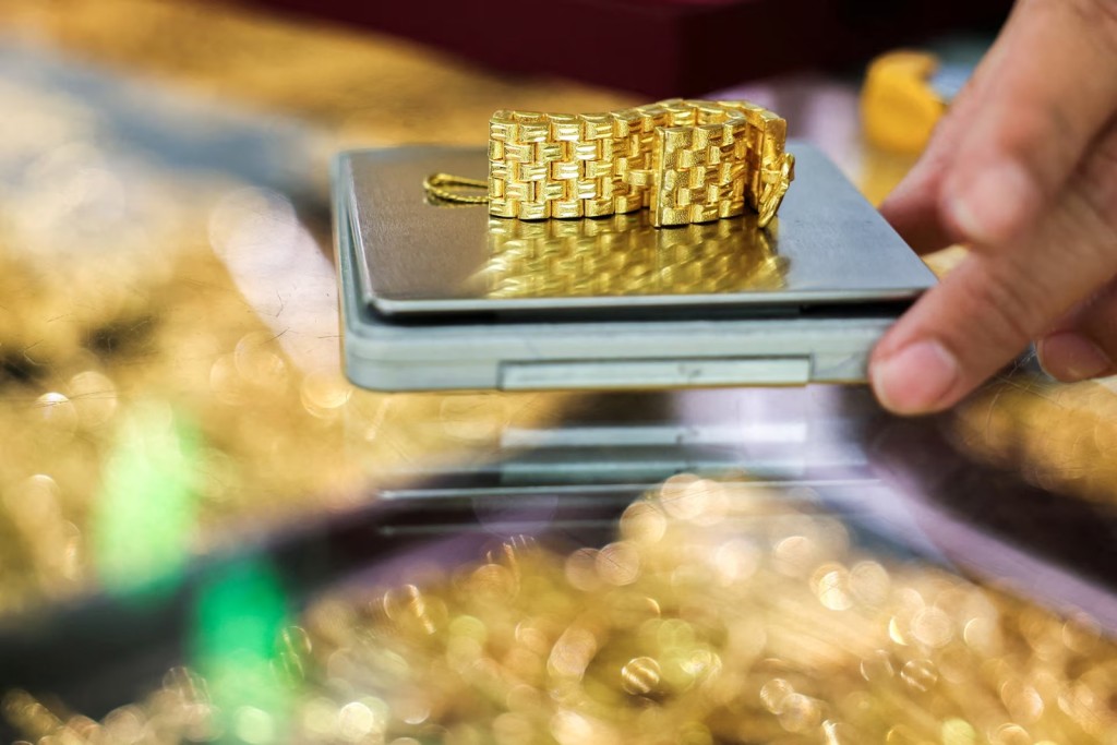 A gold seller weighs a gold watch bracelet inside a gold shop, on the day that gold surges to set a fresh record high, in Bangkok, Thailand, September 22, 2025. REUTERS