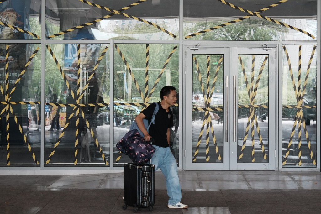 A passenger walks past glass windows taped at a temporary waiting room at Hangzhou railway station in eastern China's Zhejiang province on August 9, 2026, as a precaution against Typhoon Dolphin.(AFP)