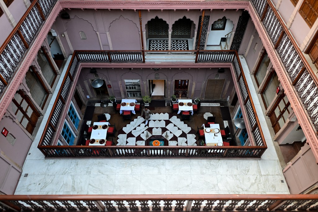 Photo by MANAN VATSYAYANA / AFP  This photograph taken on February 2, 2026 shows a hospitality staff walking across a courtyard of the Dharampura Haveli, an 18th-century haveli-turned-heritage hotel in the old quarters of Delhi.