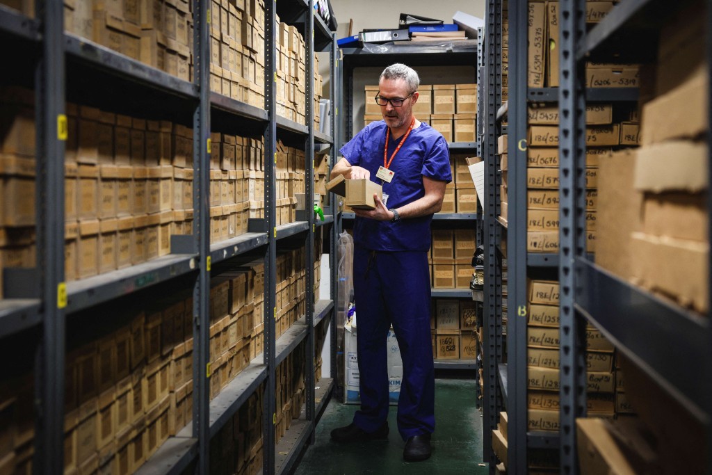 Photo by ADRIAN DENNIS / AFP  This photo taken on January 14, 2026 shows consultant gastroenterologist Kevin Monahan looking through samples in a storeroom at St Mark’s hospital at Northwick Park in Harrow, west London.