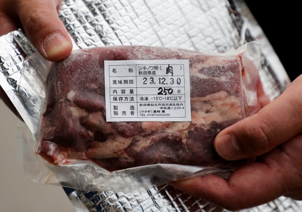 Daishi Sato, owner of Soba Noodle restaurant and the vending machine, shows a pack of Asian Black Bear meat next to the vending machine offering Asian Black Bear meat, Akita Beef and dried mountain stream fish, in front of his restaurant in Semboku, Akita prefecture, Japan Aprils 6,2023. REUTERS/Irene Wang