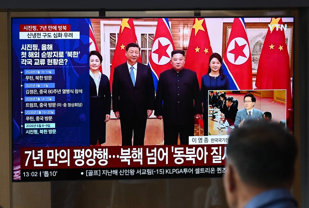 A man watches a television screen showing a news broadcast with file footage of the 2019 meeting between China's President Xi Jinping and North Korean leader Kim Jong Un, at a train station in Seoul on June 8, 2026. (AFP)