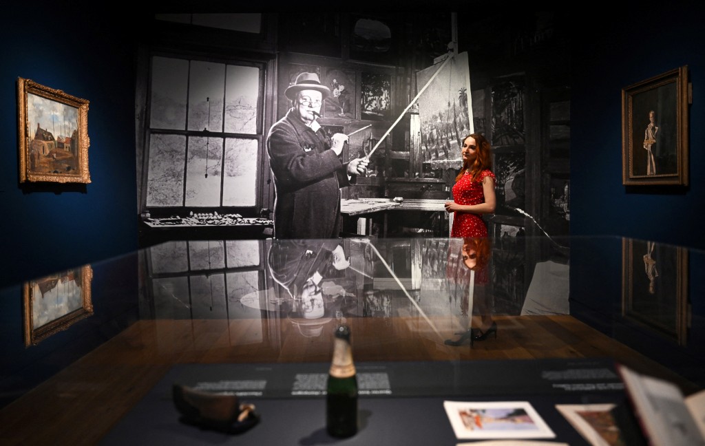 Photo by JUSTIN TALLIS / AFP A gallery assistant poses for a photograph (C) by photographer Hans Wild at the "Winston Churchill: The Painter" exhibition at the Wallace Collection in central London on May 20, 2026.