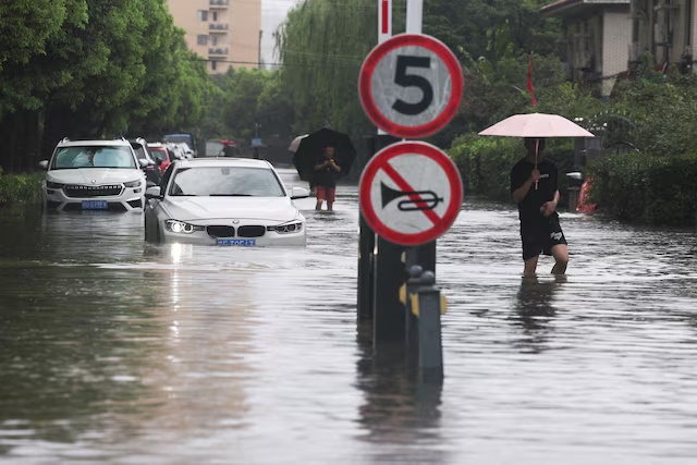 People wade through a flooded street after Typhoon Dolphin brought heavy rain to Shanghai, China, August 10, 2026. REUTERS/Go Nakamura/File Photo