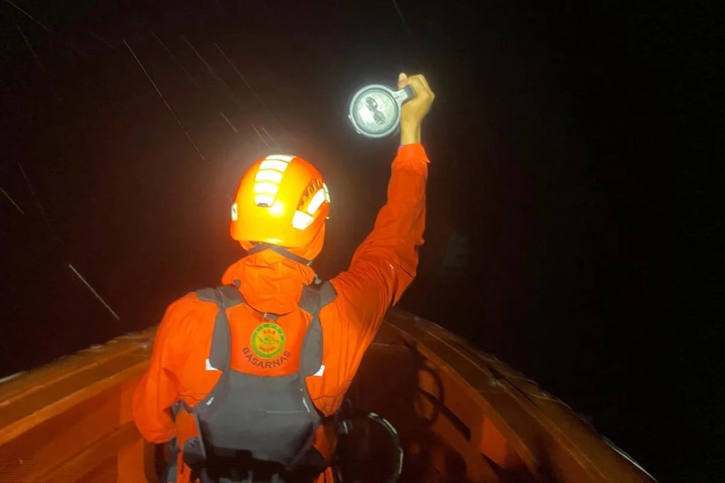 A rescuer uses a torchlight to search for survivors after a boat capsized on July 14 in Indonesia (AP)