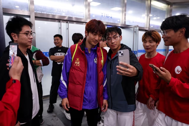 Volunteers take selfies with Nantong team's captain Li Xiancheng after his training, before the 2025 Jiangsu Football City League final, also known as Jiangsu Super League (JSL), at Nanjing Olympic Sports Center in Nanjing, Jiangsu province, China October 31, 2025. REUTERS/Tingshu Wang 