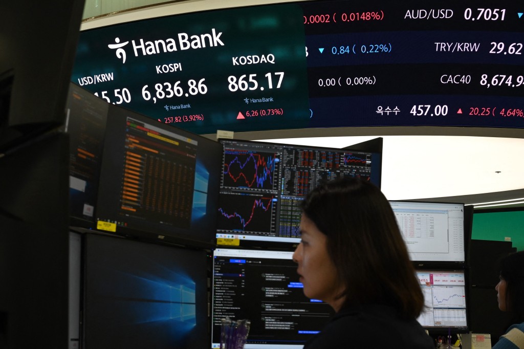 A dealer works near a screen showing South Korea benchmark KOSPI stocks index in a foreign exchange dealing room at the Hana Bank headquarters in Seoul on August 13, 2026. AFP