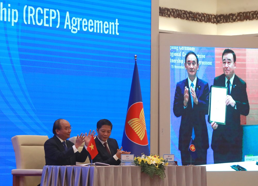 Vietnamese Prime Minister Nguyen Xuan Phuc, left, and Minister of Trade Tran Tuan Anh, right, applaud next to a screen showing Japanese Prime Minister Yoshihide Suga and Minister of Trade Hiroshi Kajiyama holding up signed RCEP agreement, in Haoni. Vietnamese Prime Minister Nguyen Xuan Phuc, left, and Minister of Trade Tran Tuan Anh, right, applaud next to a screen showing Japanese Prime Minister Yoshihide Suga and Minister of Trade Hiroshi Kajiyama holding up signed RCEP agreement, in Haoni.