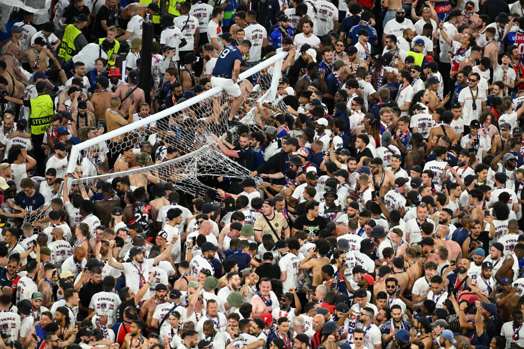 Paris St Germain fans invade the pitch as one fan climbs on the goal after winning the Champions League. (Reuters)