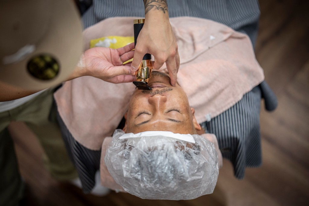Photo by YUICHI YAMAZAKI / AFP  This photo taken on August 27, 2026 shows Tekisasu, an active yakuza gangster allied to a major clan, having his beard trimmed at a barbershop in Tokyo.