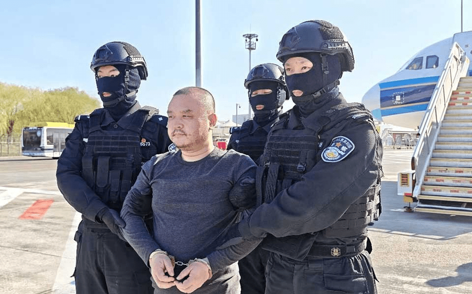Alleged scam center kingpin Li Xiong detained by Chinese security forces upon arrival in Beijing after being repatriated from Cambodia on April 1, 2026. Image via the Chinese Ministry of Public Security.