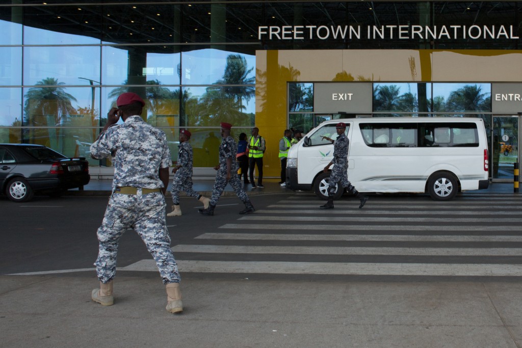 Photo by - / AFP  Security escort migrants in a National Public Health Agency (NPHA) after their arrival at Freetown International Airport, formerly known as Lungi International Airport, in Lungi on May 20, 2026.
