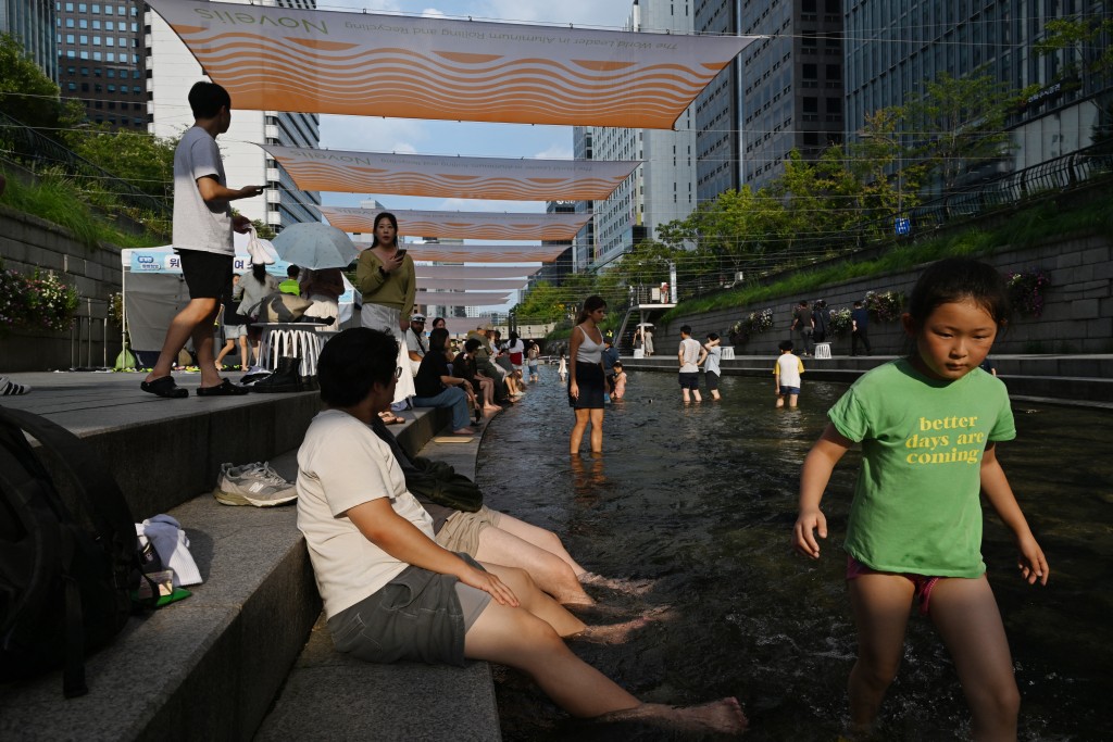 Residents cool off below sunshades over the Cheonggyecheon Stream in Seoul on August 3, 2026. (AFP)