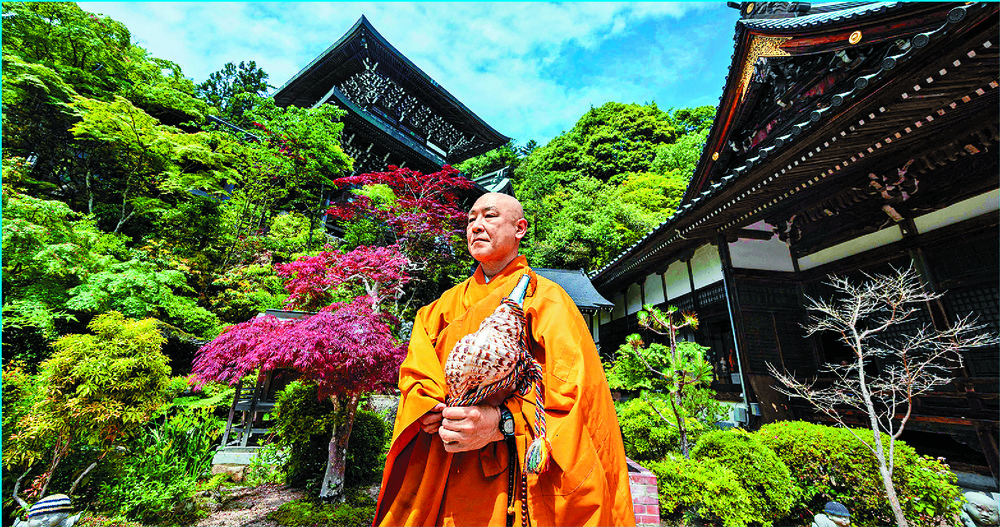 Yoyu Mimatsu cradles the conch to sound it at a ceremony to burn thousands of paper cranes at Daisho-in Buddhist temple on Miyajima, near Hiroshima. 