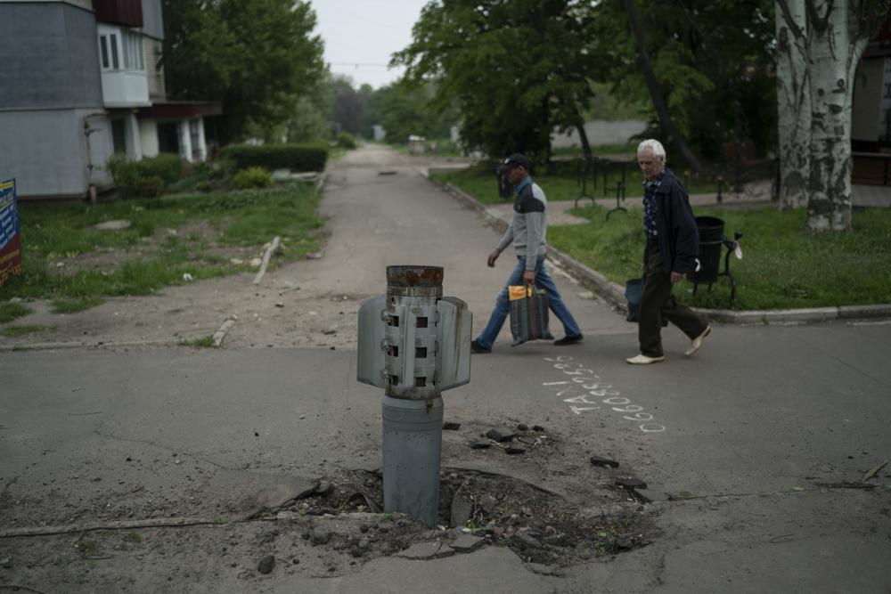 People walk past part of a rocket that sits wedged in the ground in Lysychansk, Luhansk region, Ukraine. (AP) People walk past part of a rocket that sits wedged in the ground in Lysychansk, Luhansk region, Ukraine. (AP)
