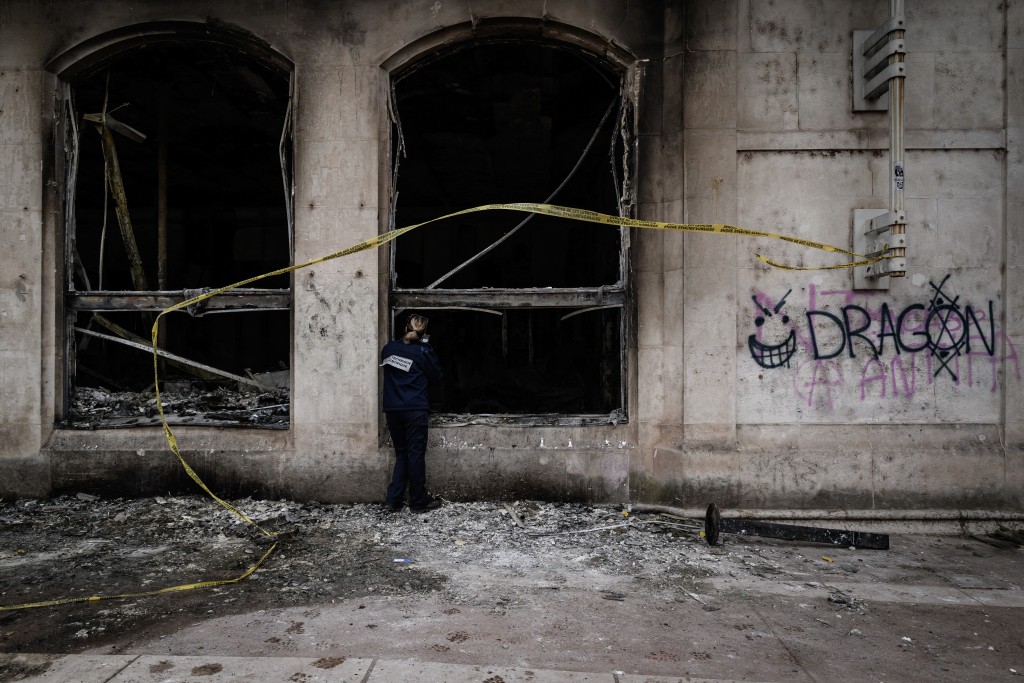 A forensic officer examines the burnt Lyon Office de Tourisme a day after riot and looting following a nationwide protest against the "high cost of living", in Lyon central-eastern France on October 18, 2026.