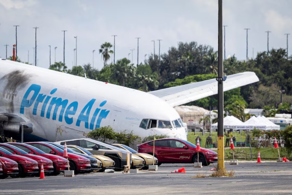 Tesla cars are parked in a lot next to where a crashed Amazon Prime Air cargo plane came to rest, where airport officials said it overran a runway at Miami International Airport, in Miami, Florida, U.S., September 7, 2026. REUTERS/Marco Bello